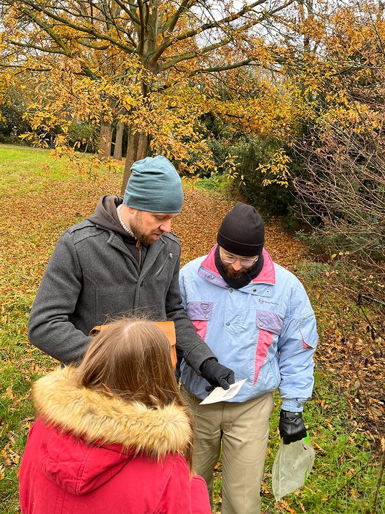 Team 2 schaut sich in herbstlicher Landschaft einen gefundenen Hinweis an