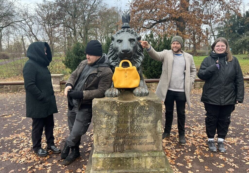 Team 1 posiert im Herrenkrugpark bei der Löwenstatue